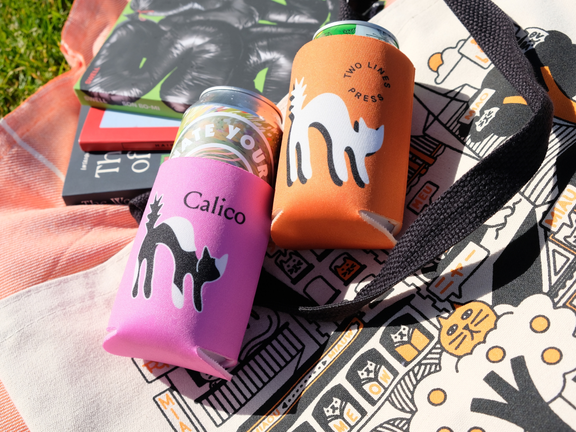 Photo featuring Two Lines Press koozies, tote bag and books